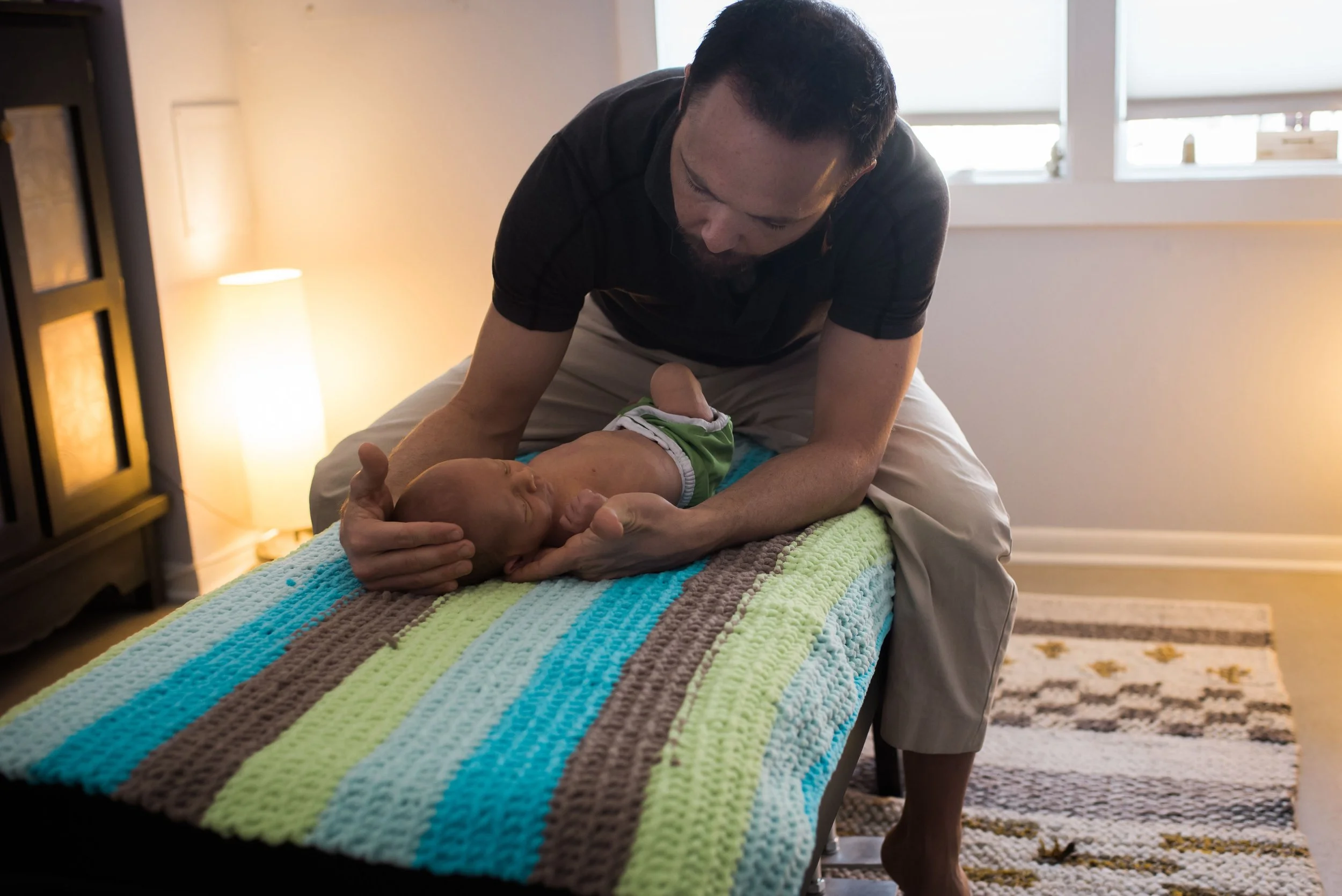 Dr. Dylan adjusting newborn on colorful blanket